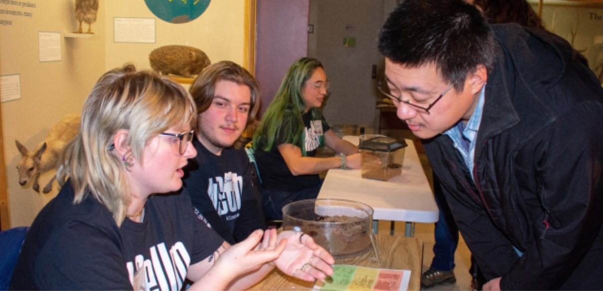 Students displaying insects to observers at an exhibition