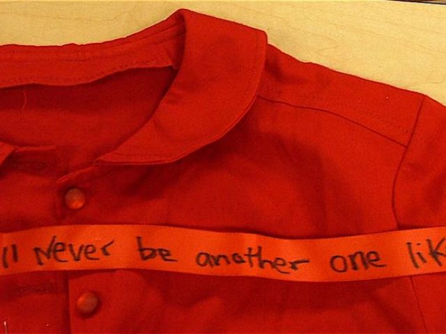 Closeup of a red dress collar with red tape that reads 