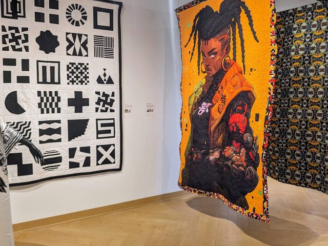 Black and white pieces from MSU Museum's Collections on display next to modern painted quilts