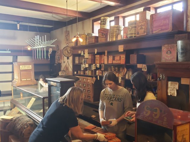 A class of college students at the MSU Museum assisting with collections items in a turn of the century general store.