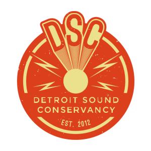 Logo of the Detroit Sound Conservancy, featuring a circular red-orange badge with a stylized design. The acronym 'DSC' appears in bold, cream-colored letters at the top, with lines radiating downward to a central circle. The words 'Detroit Sound Conservancy' are written in cream text below, with 'EST. 2012' at the bottom.